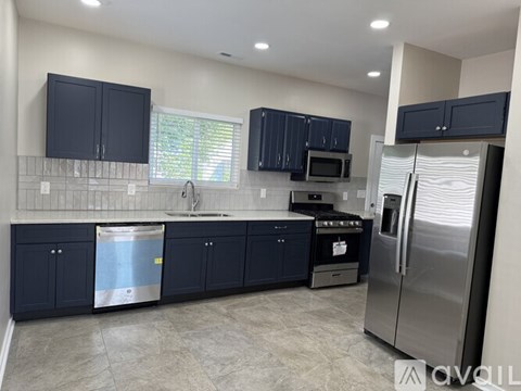 A kitchen with dark blue cabinets and stainless steel appliances.