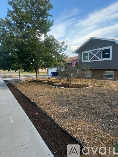 A grey house with a tree in front of it.