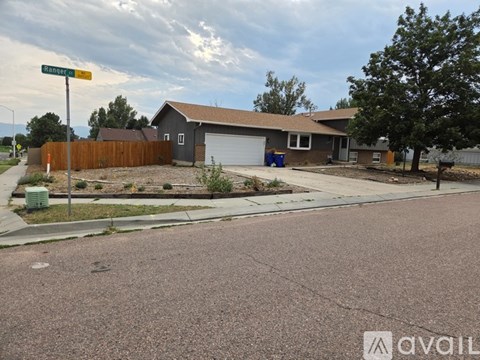A residential street with a house and a street sign.