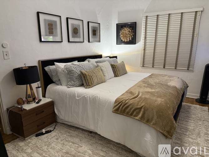 A bedroom with a large bed and a nightstand with a lamp.