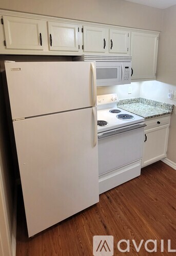 A white refrigerator in a kitchen with wooden floors.