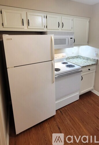 A white refrigerator in a kitchen with wooden floors.