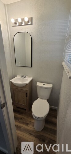 A bathroom with a toilet, sink, and mirror.