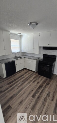 A kitchen with white cabinets and a wooden floor.