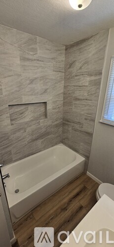 A bathroom with a white bathtub and a stone wall.