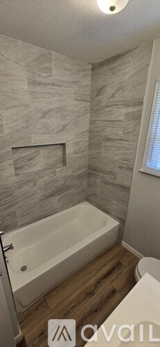 A bathroom with a white bathtub and a stone wall.