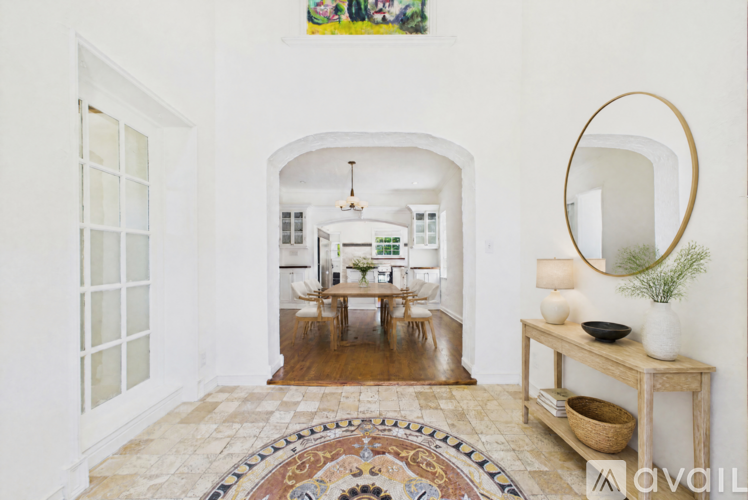 A room with a white wall and a round mirror on the right side.