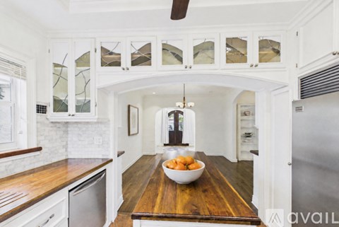 A kitchen with a wooden table and a bowl of oranges on it.