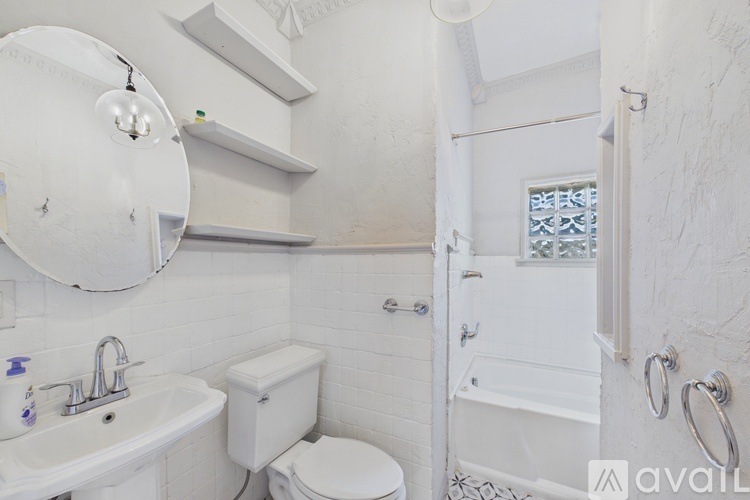 A white bathroom with a toilet, sink, and shower.