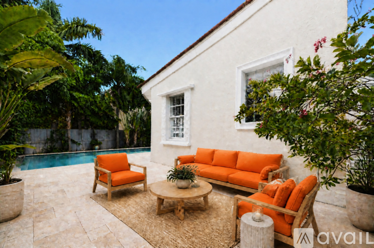 A white house with a pool and orange furniture.
