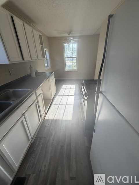 A kitchen with white cabinets and a window.