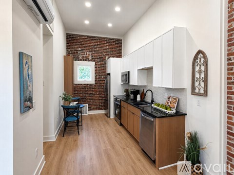 A kitchen with a brick wall and wooden floors.