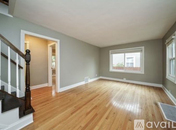 A room with wooden floors and a window with a view of a building outside.