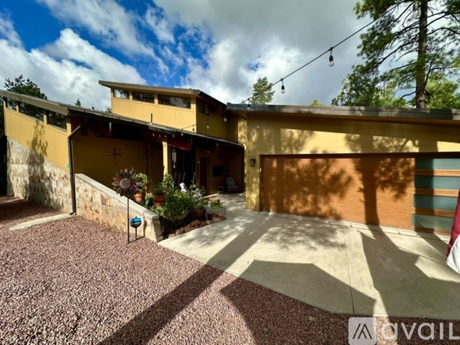 A yellow house with a gravel driveway and a small garden.