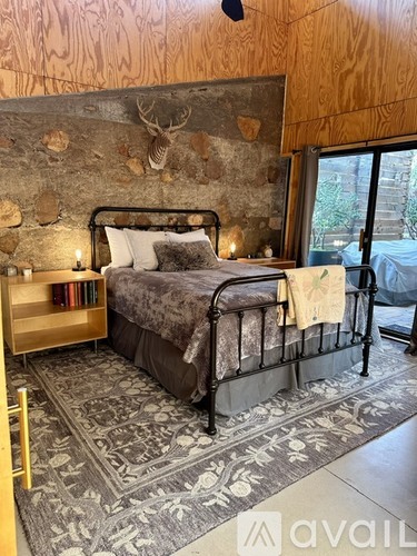 A bedroom with a large bed and a stone wall.