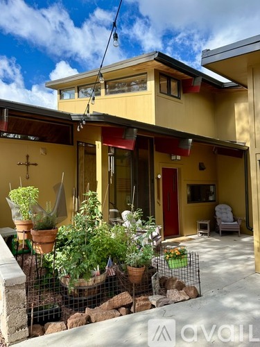 A yellow house with a red door and a patio with a table and chairs.