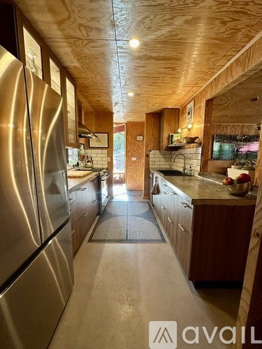 A modern kitchen with wooden cabinets and a stainless steel refrigerator.