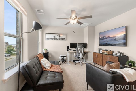 A living room with a black couch and a ceiling fan.