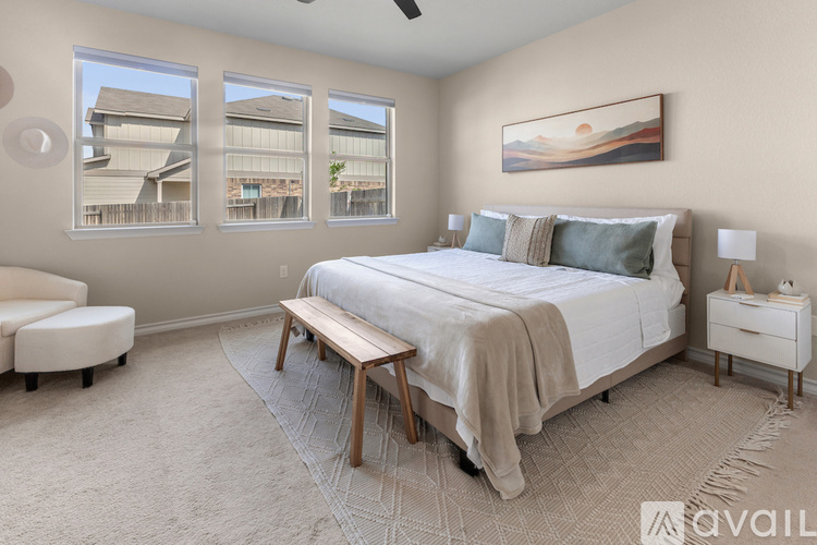 A bedroom with a large bed, a bench, and a painting on the wall.