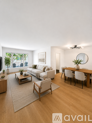 A living room with a white couch, a wooden coffee table, and a dining table with chairs.