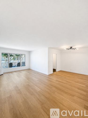 A room with wooden flooring and a window overlooking a cityscape.