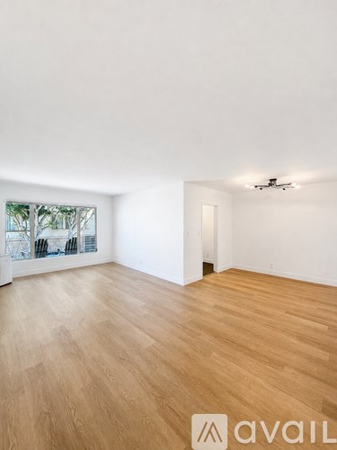 A room with wooden flooring and a window overlooking a cityscape.