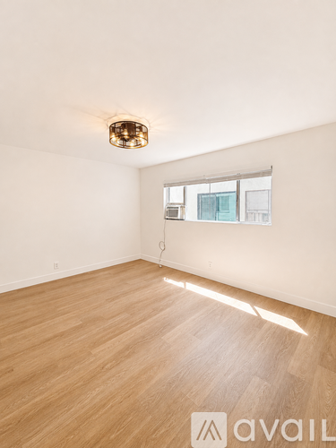 A room with wooden flooring and a window letting in natural light.