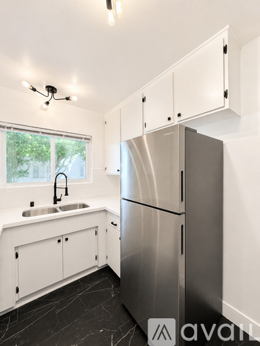 A kitchen with a sink, refrigerator, and cabinets.