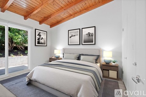 A bedroom with a large bed and a wooden ceiling.