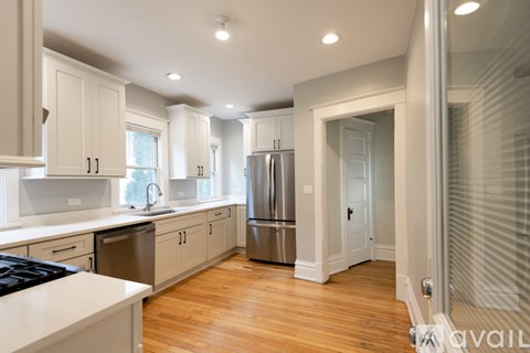 A modern kitchen with wooden floors and stainless steel appliances.