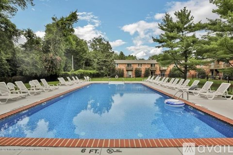 A 6 foot pool surrounded by lounge chairs.