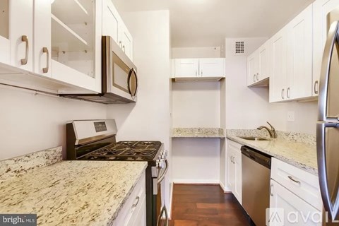A kitchen with white cabinets and a granite countertop.