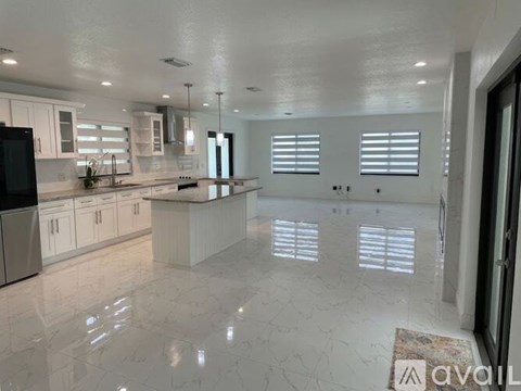 A modern kitchen with white cabinets and a marble floor.