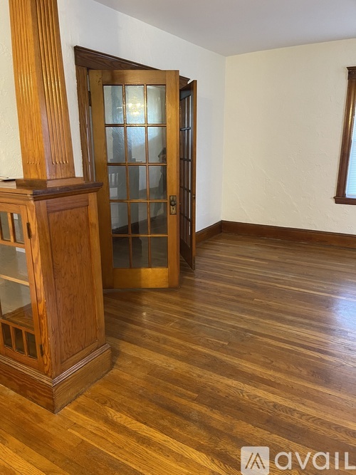A room with wooden floors and a wooden cabinet with glass doors.