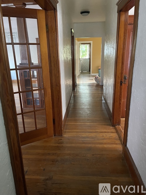 A long hallway with wooden floors and doors on either side.