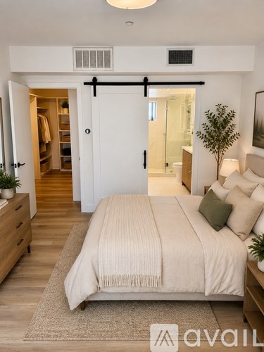 A bedroom with a bed, dresser, and a plant.