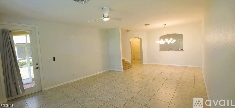 A spacious room with tiled flooring and a mirror on the wall.
