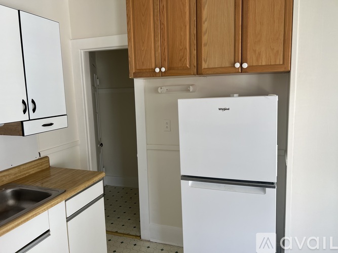 A white fridge in a kitchen with wooden cabinets.