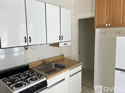 A kitchen with white cabinets and a stove top oven.