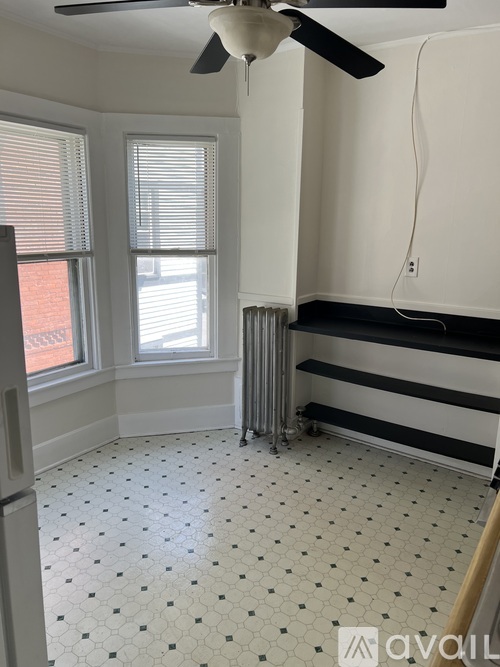 A room with a ceiling fan and a radiator on the floor.