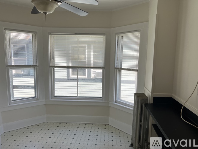A room with a ceiling fan and three windows with blinds.