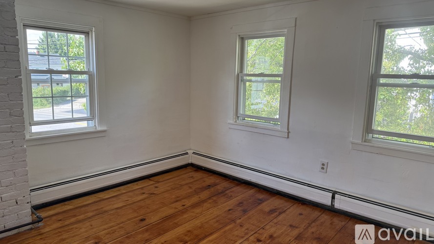 A room with wooden floors and two windows.