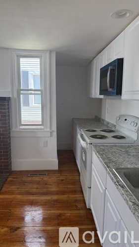 A kitchen with white cabinets and a wooden floor.