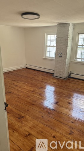 A room with wooden floors and a white brick pillar.