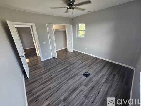 A room with a ceiling fan and wooden flooring.