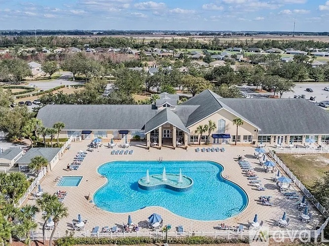 An aerial view of a resort with a large swimming pool and a building in the background.