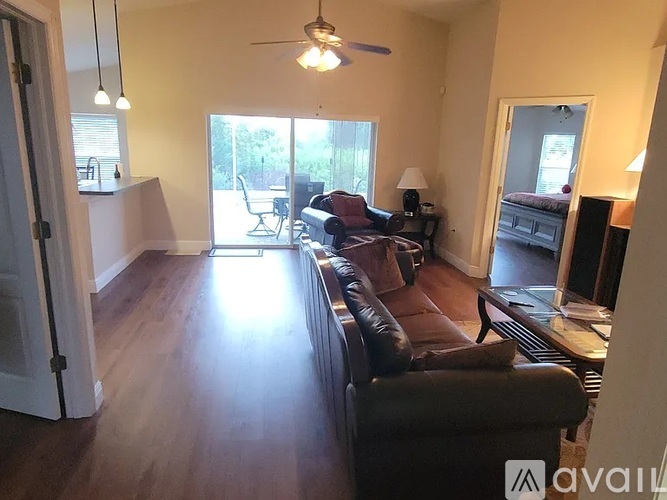 A living room with a brown leather couch and a ceiling fan.