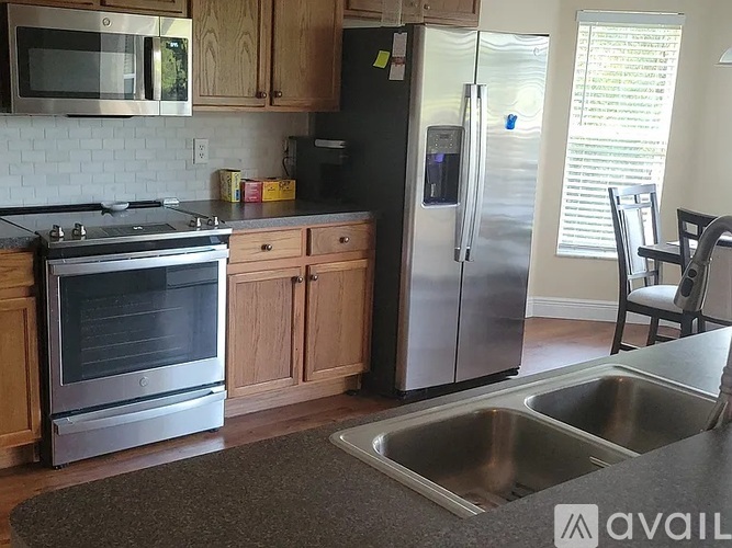 A kitchen with a stove, refrigerator, and sink.