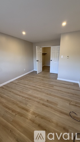 A room with wooden flooring and a doorway leading to another room.
