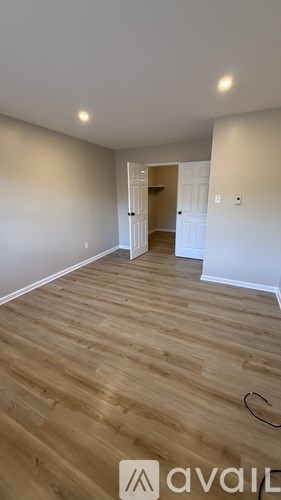 A room with wooden flooring and a doorway leading to another room.